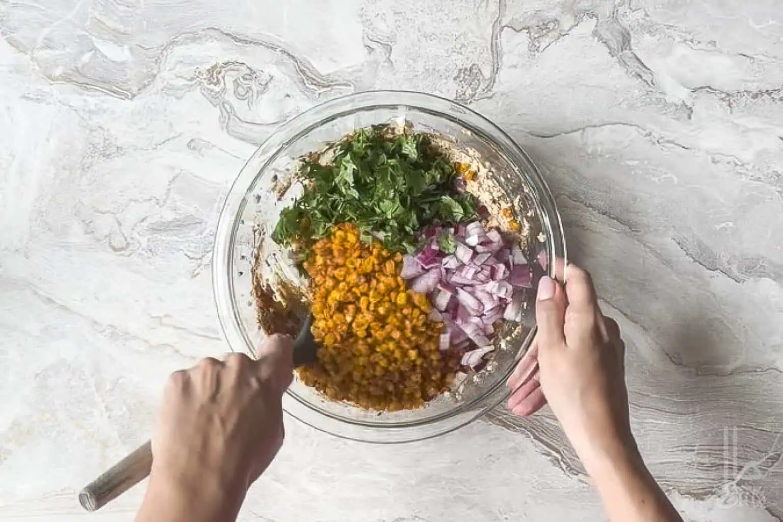 stirring cilantro, red onion, and charred corn kernels into the elote dip.