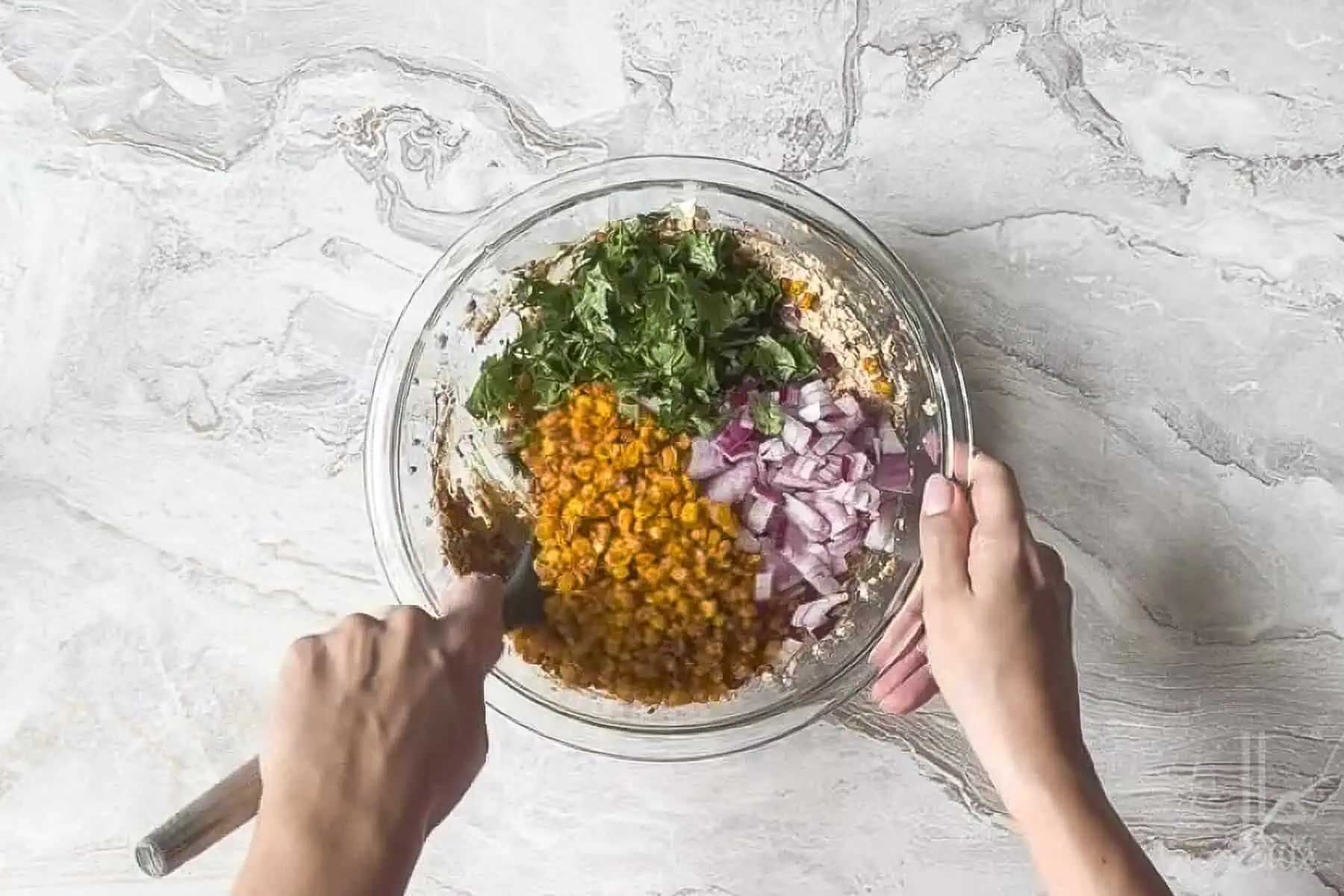 stirring cilantro, red onion, and charred corn kernels into the elote dip.