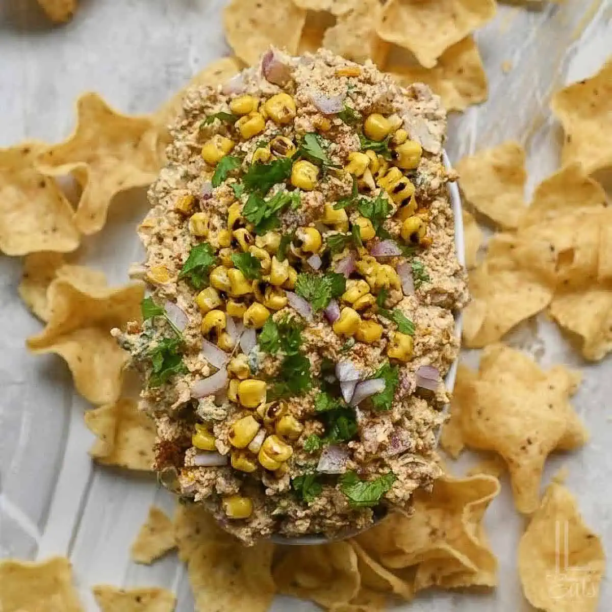 cold elote (mexican street corn) dip, surrounded by scoopable tortilla chips.