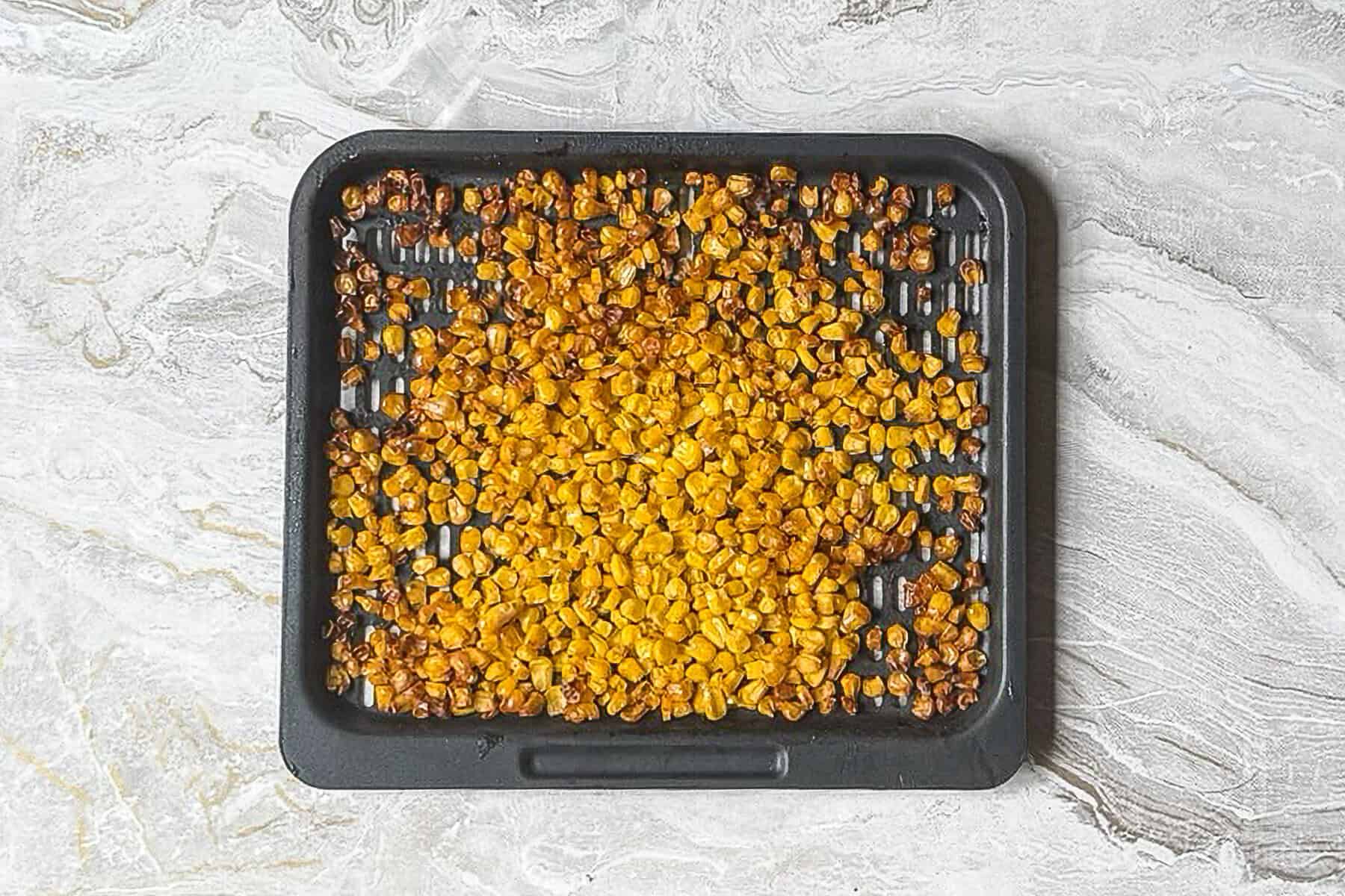 charred corn kernels on an air fryer pan.