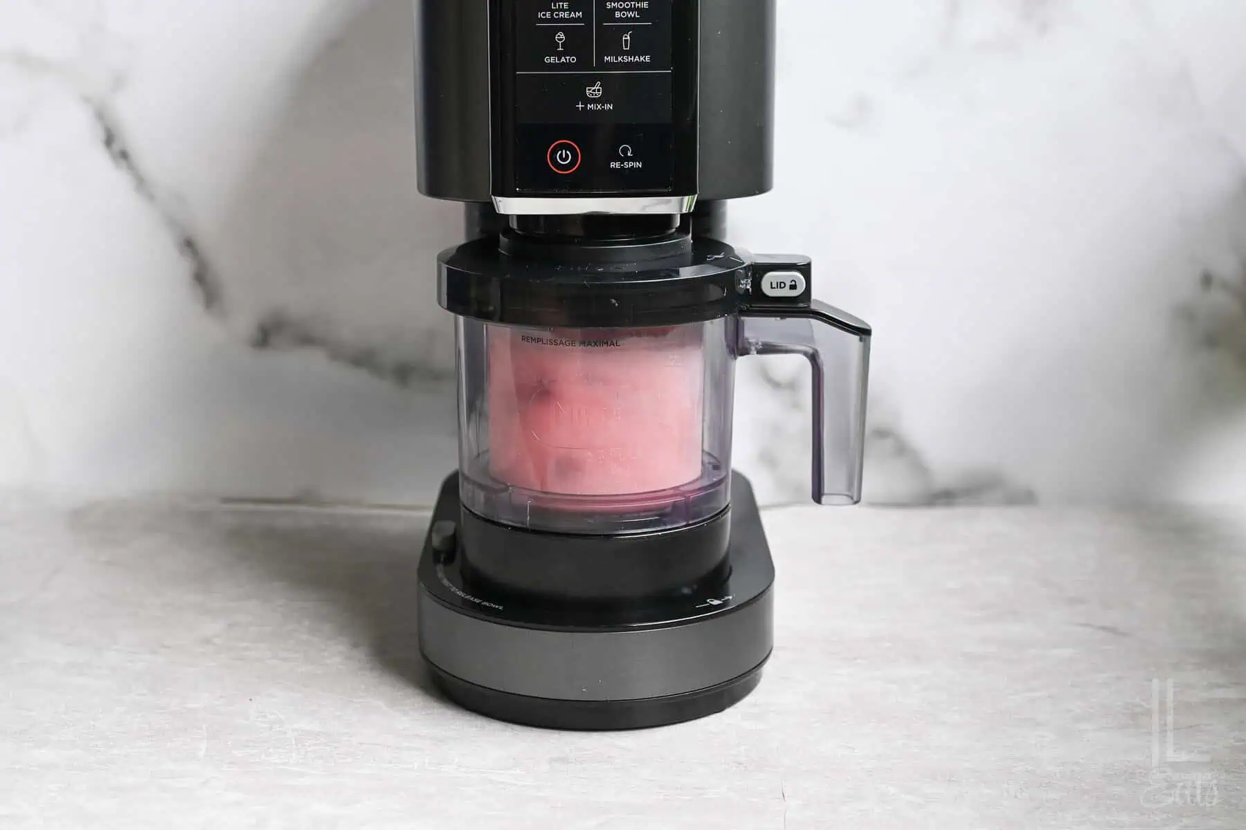 strawberry ice cream being blended in a ninja creami machine.