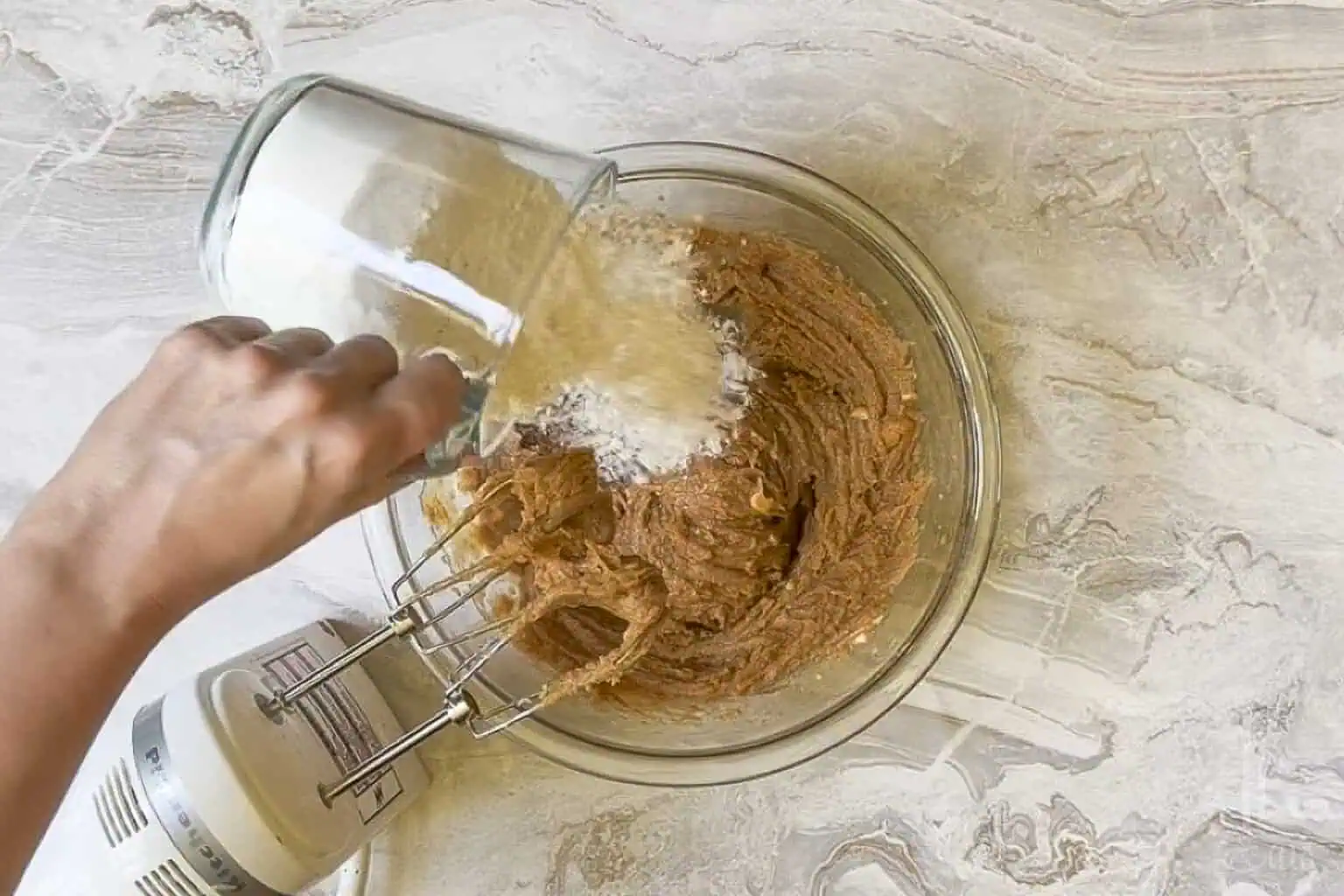 adding flour to the wet ingredients for peanut butter cookie bars.