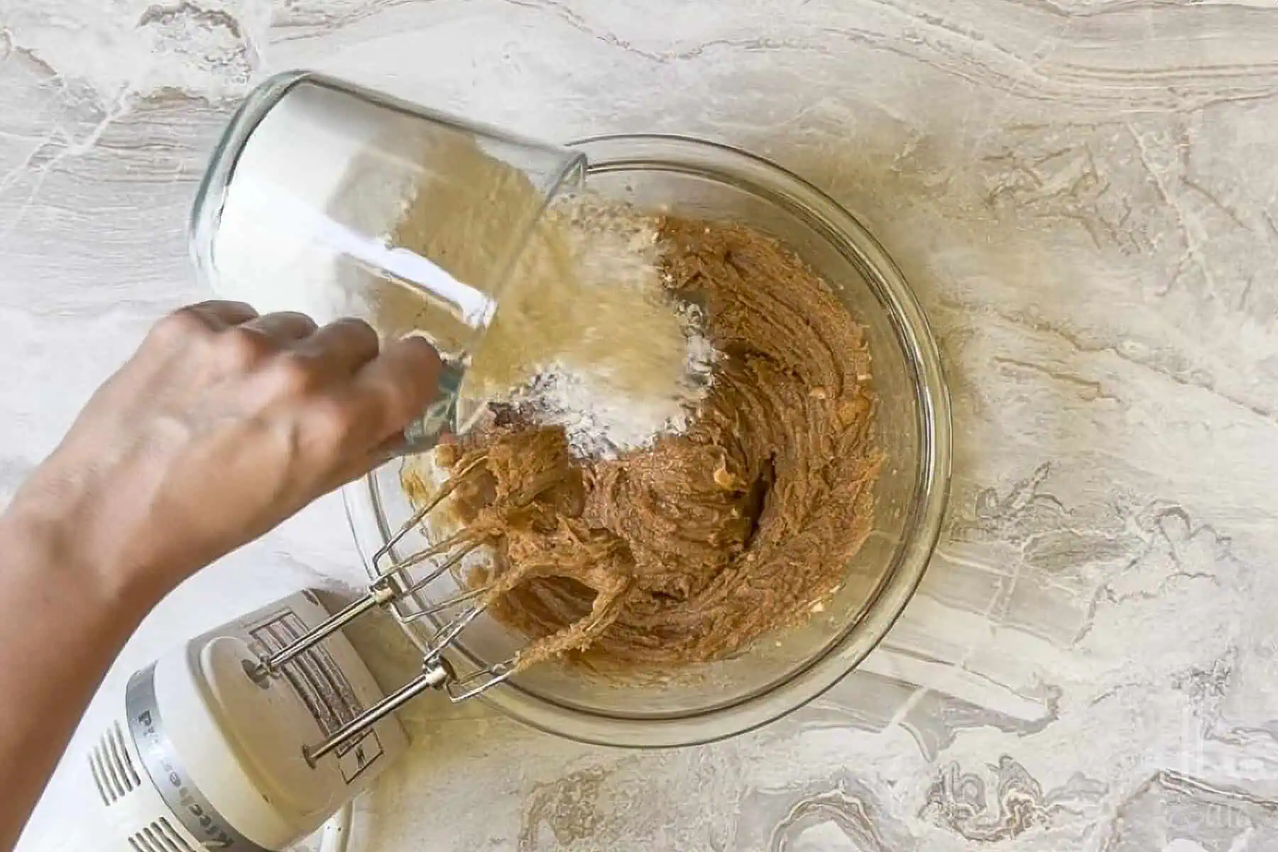 adding flour to the wet ingredients for peanut butter cookie bars.