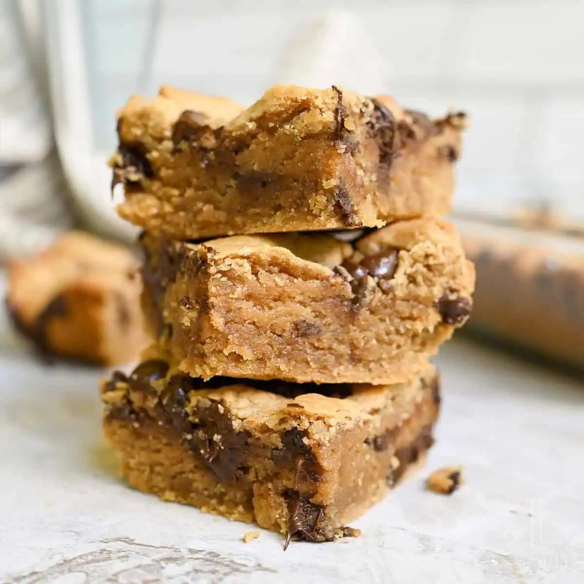 stack of peanut butter cookie bars, showing melted chocolate chips.