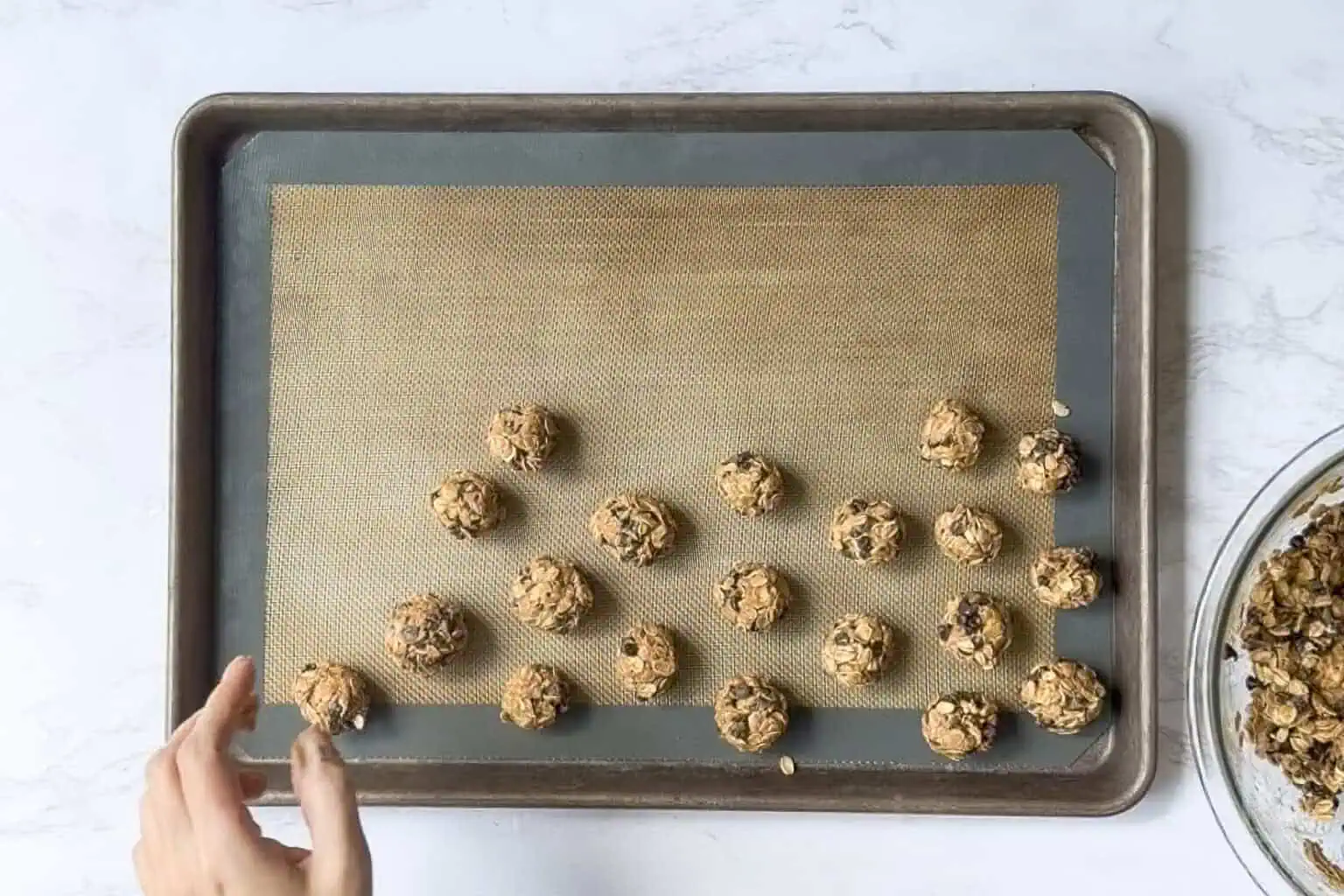 rolling peanut butter oatmeal balls on a cookie sheet.