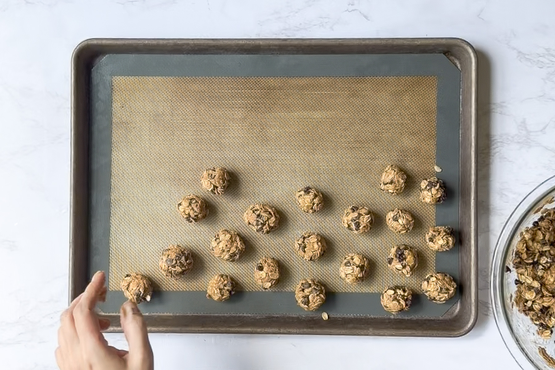 rolling peanut butter oatmeal balls on a cookie sheet.
