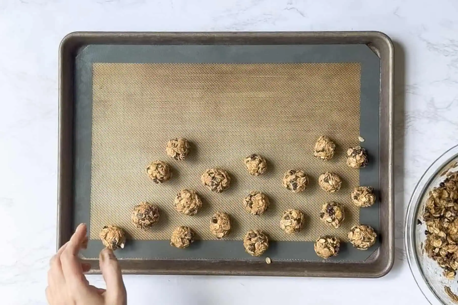rolling peanut butter oatmeal balls on a cookie sheet.
