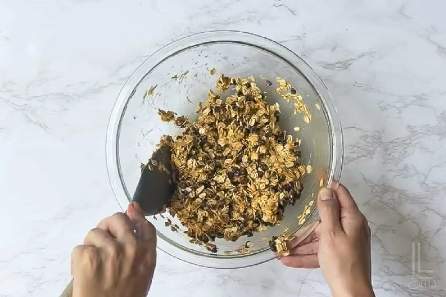 adding oats and chocolate chips into the peanut butter syrup mixture.