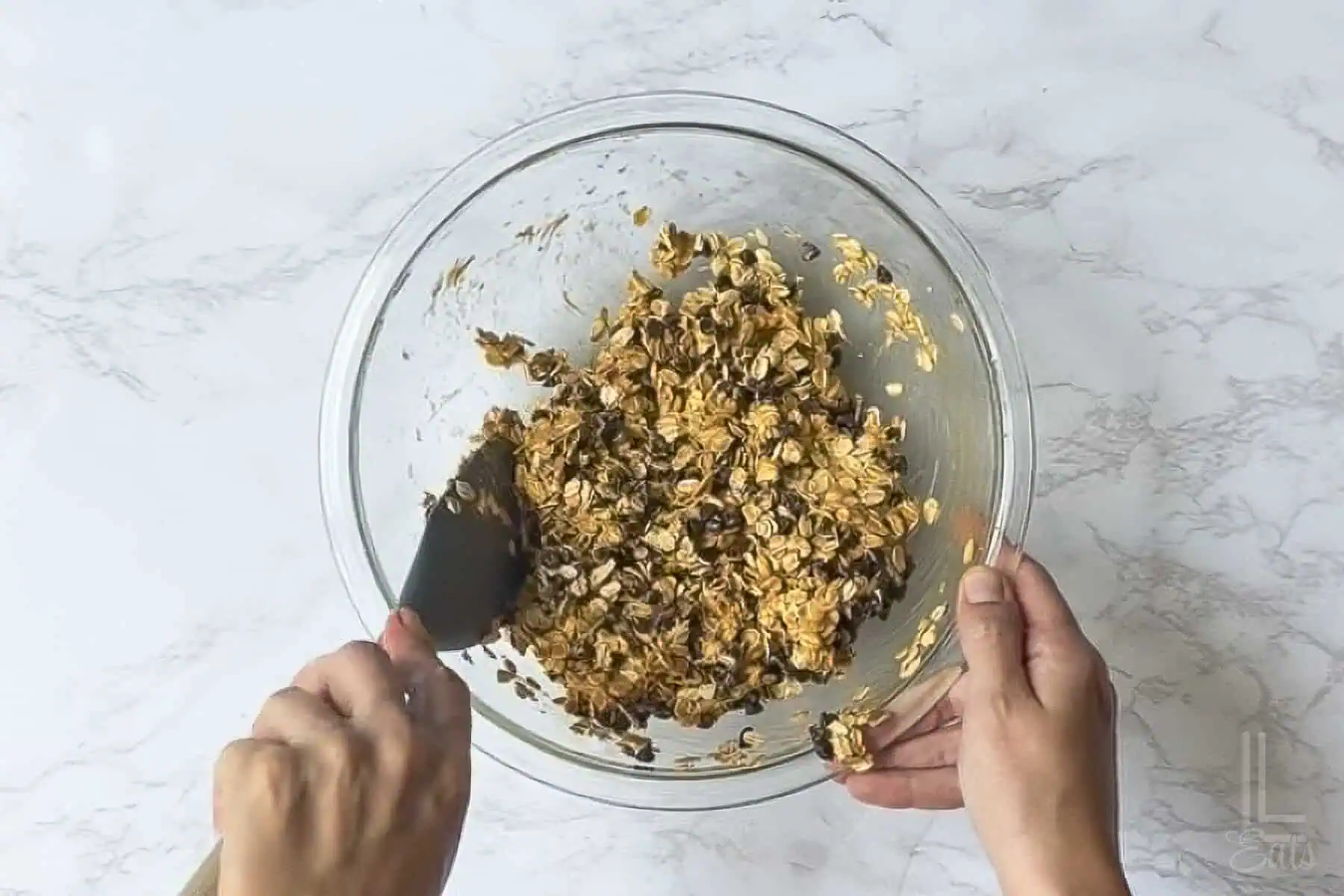 adding oats and chocolate chips into the peanut butter syrup mixture.