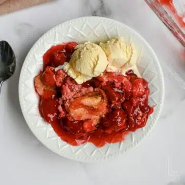 plate with strawberry dump cake and ice cream.