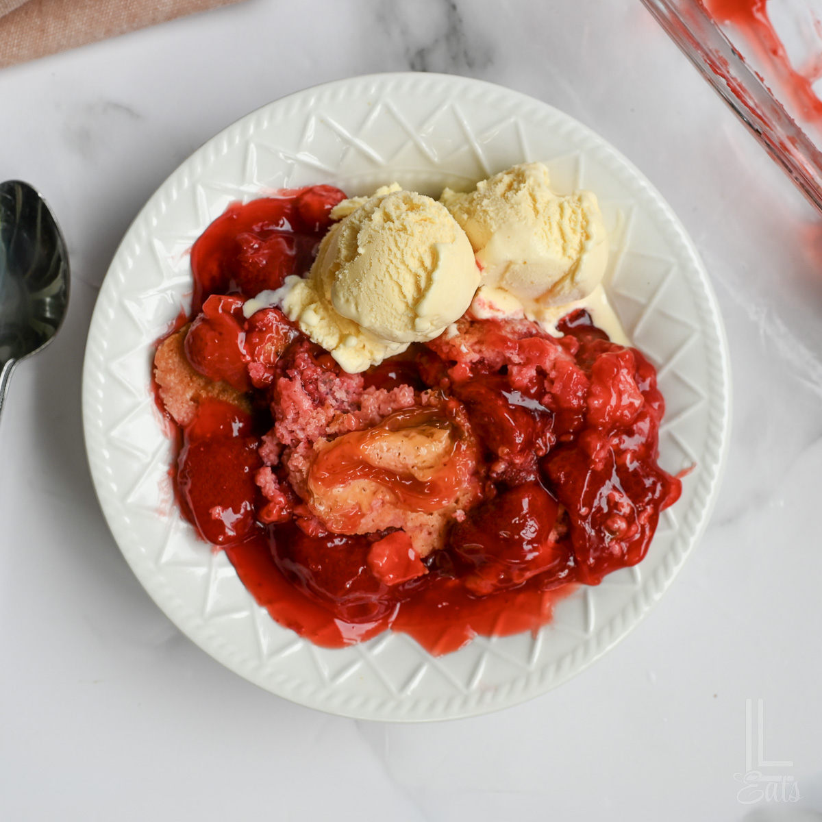 plate with strawberry dump cake and ice cream.