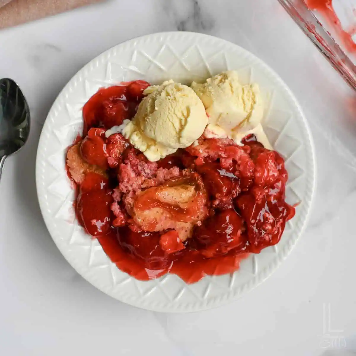 plate with strawberry dump cake and ice cream.