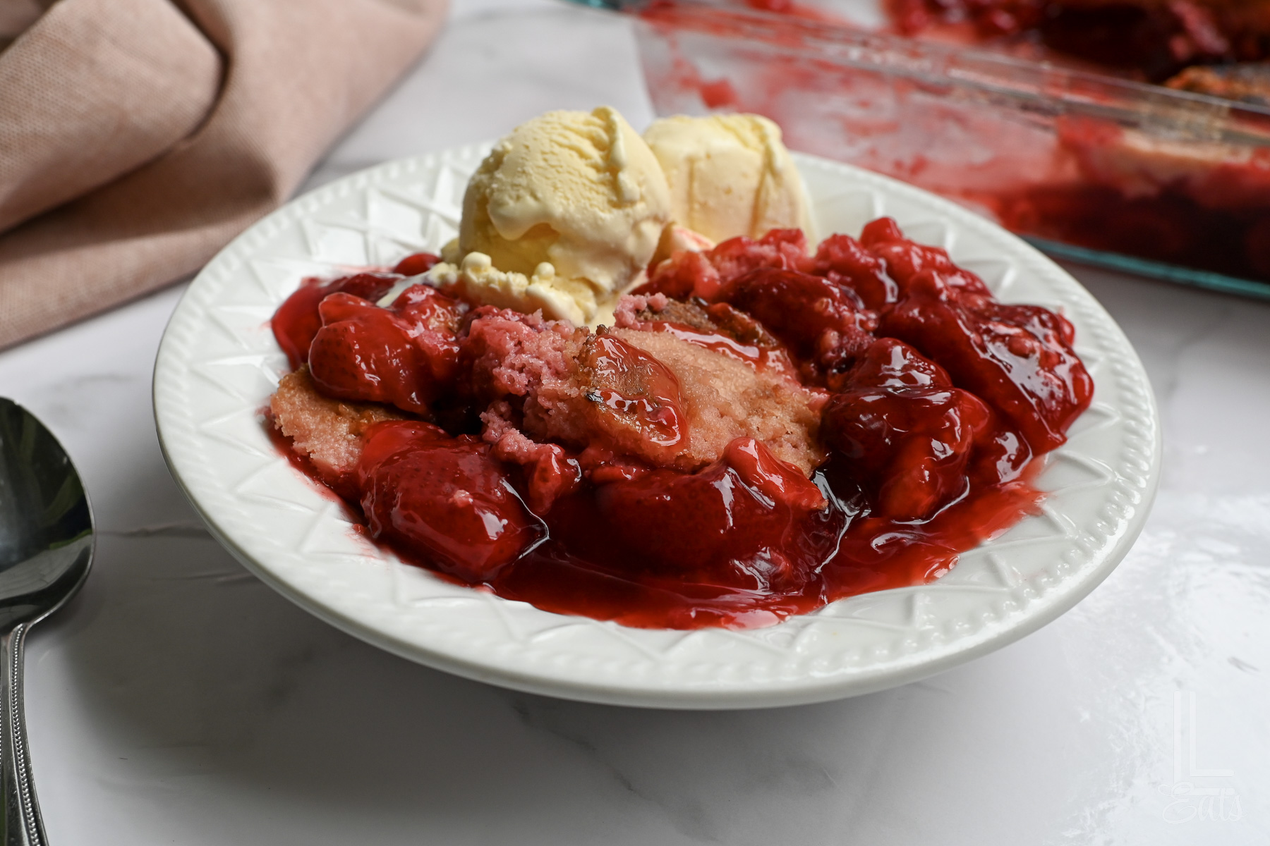 strawberry dump cake in a bowl with ice cream.