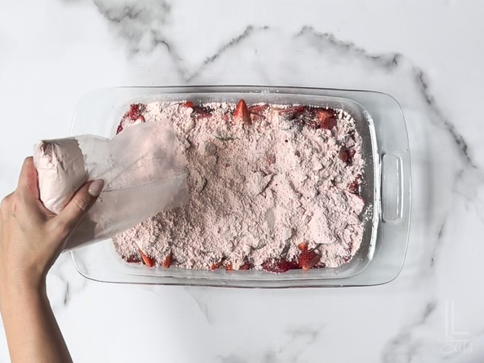 spreading dry cake mix over the strawberries.