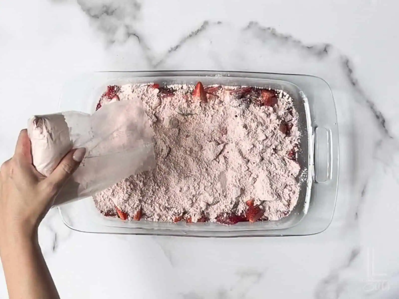 spreading dry cake mix over the strawberries.