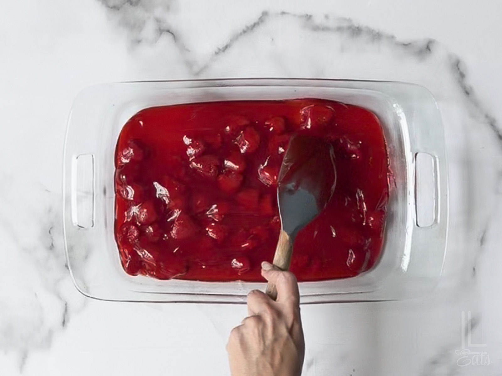 spreading starwberry pie filling in the bottom of a 9x13" dish.