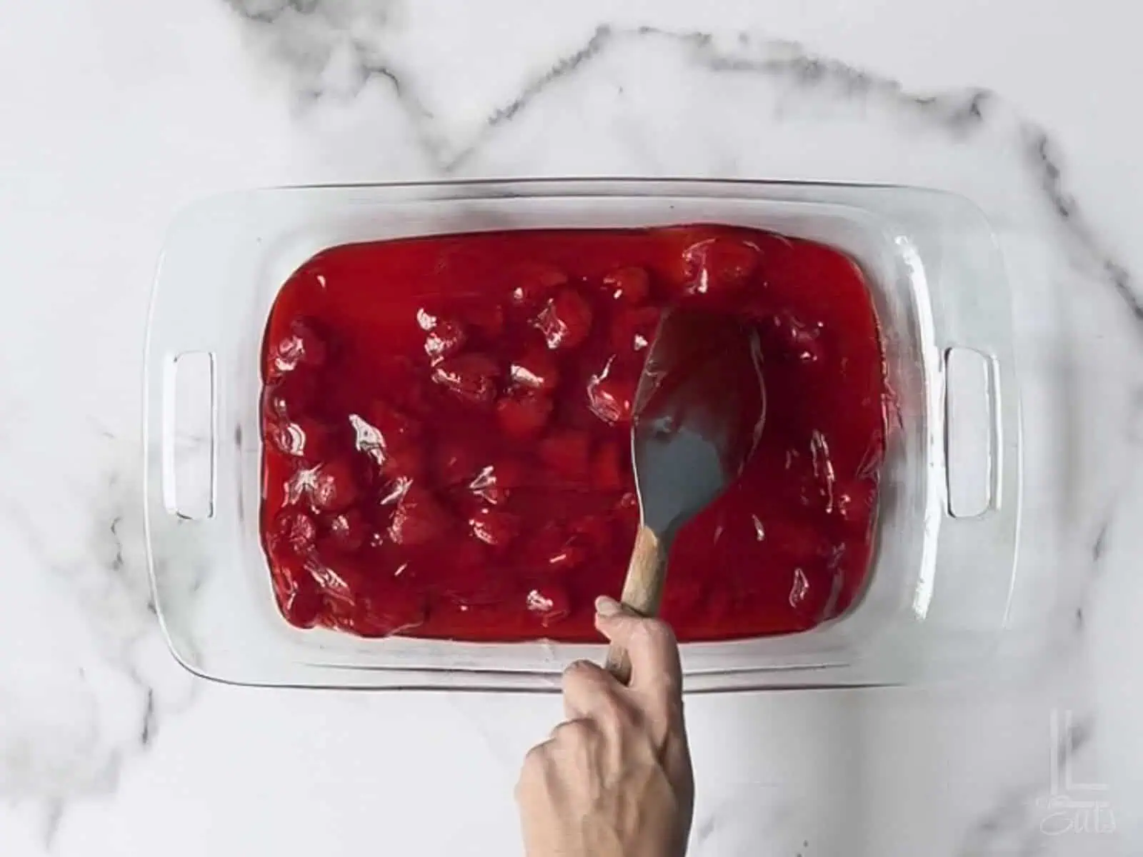 spreading starwberry pie filling in the bottom of a 9x13" dish.