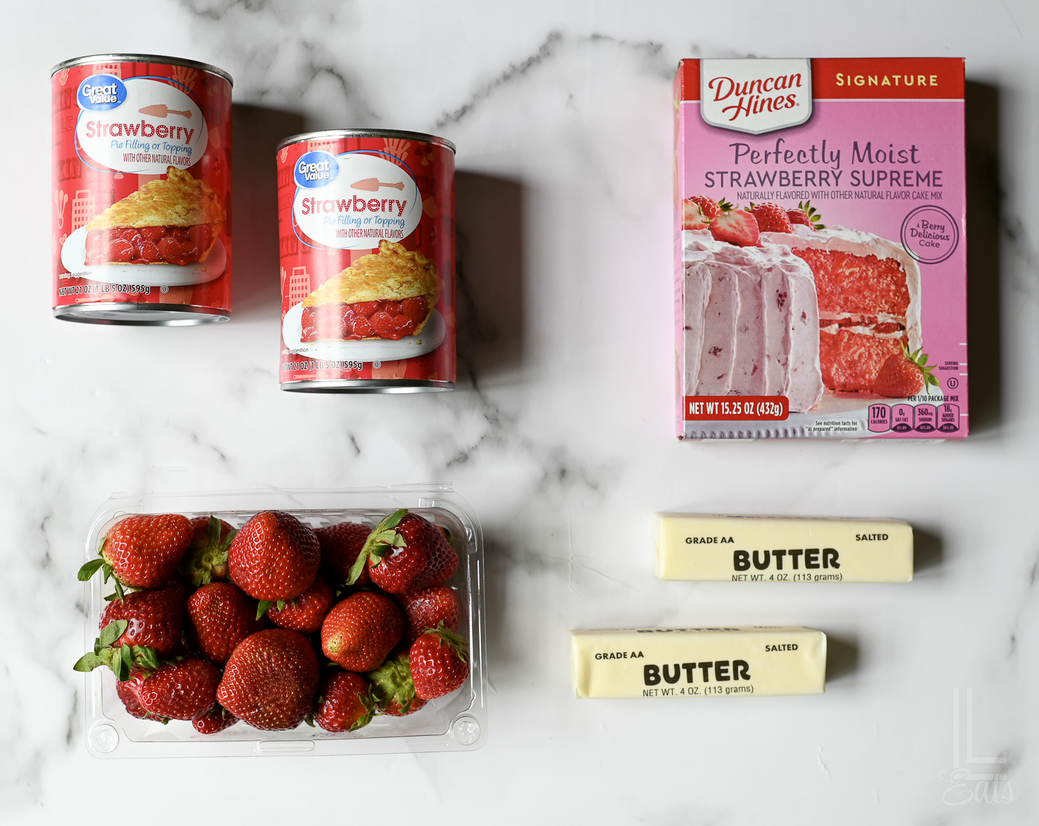 ingredients for strawberry dump cake - cake mix, strawberries, pie filling, and butter.