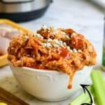 Delicious Instant Pot Buffalo Chicken served in a white bowl with celery sticks.