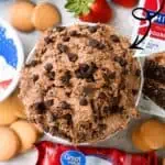 Chocolate chip cookie dough ice cream with strawberries and cookies on a table.