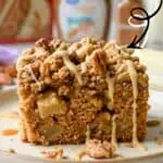 Close-up of pecan crumble apple spice cake with drizzle and fresh apples.