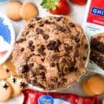 Chocolate chip brownie batter dip with strawberries and cookies on a plate.