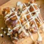 Close-up of pecan streusel apple spice cake with drizzle on wooden board.