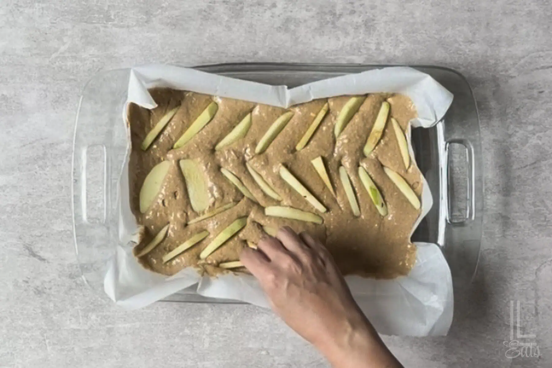 adding thin slices of peeled granny smith apples to the apple spice cake batter.