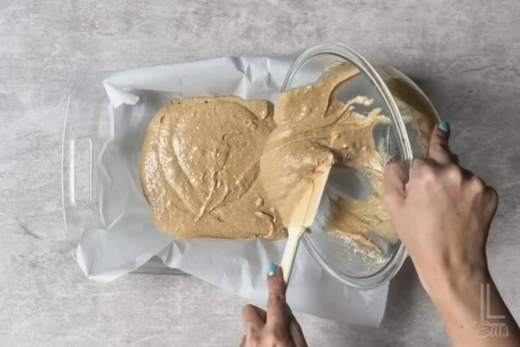 pouring the apple spice cake batter into a parchment-lined 9x13" baking dish.