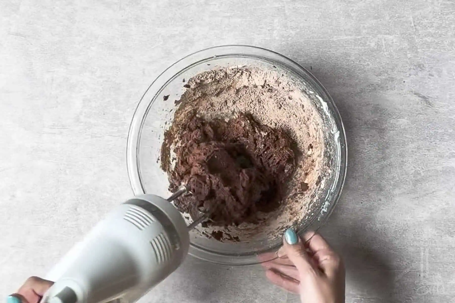 adding the heat treated brownie mix to the whipped cream cheese.