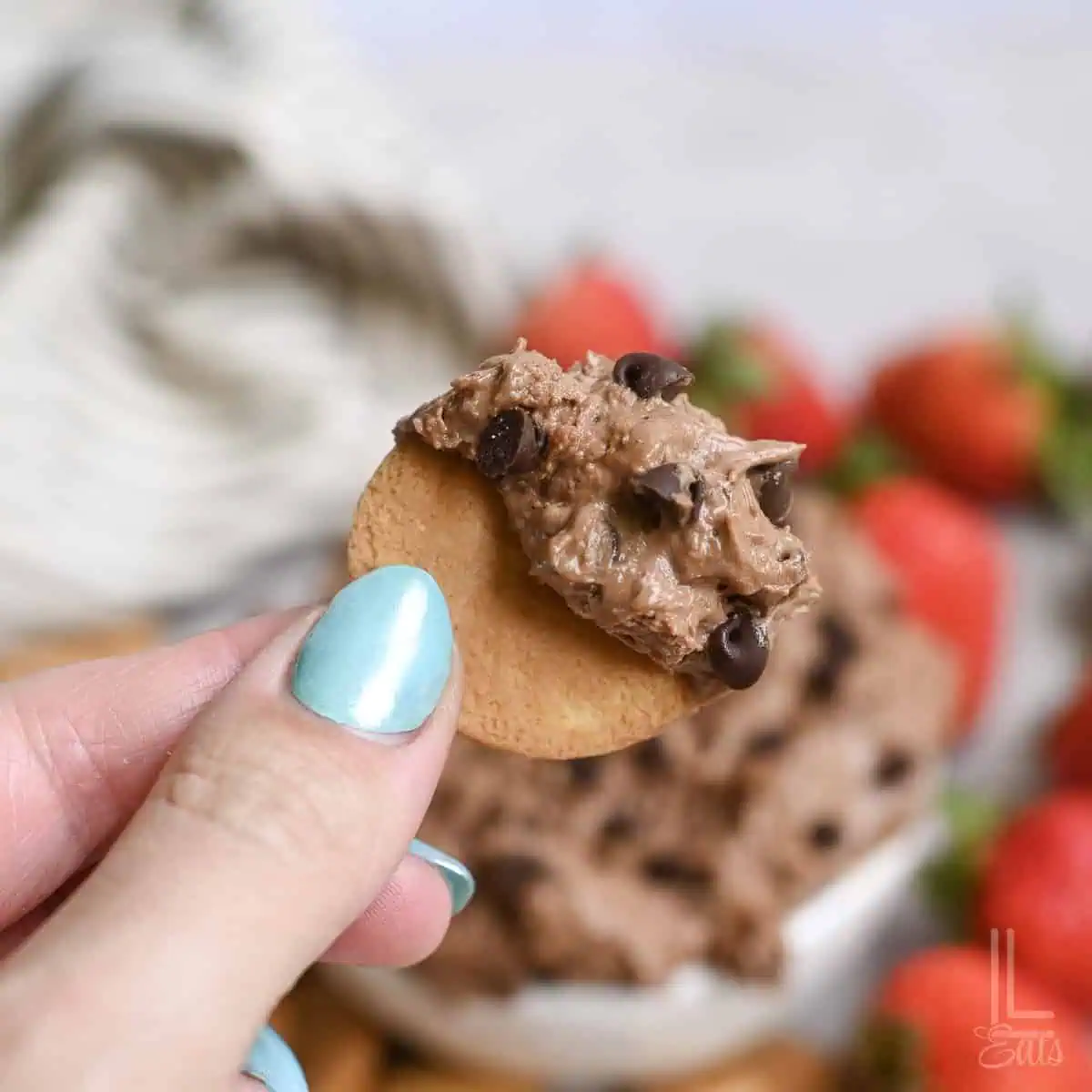 dipping a vanilla wafer into a bowl of brownie batter dip.