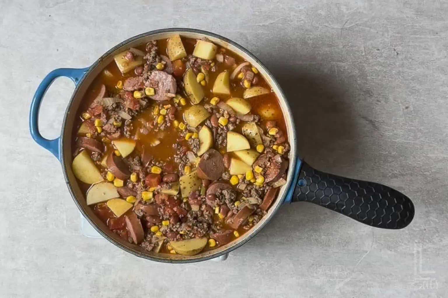 cowboy stew, with potatoes added, simmering in a large pot.