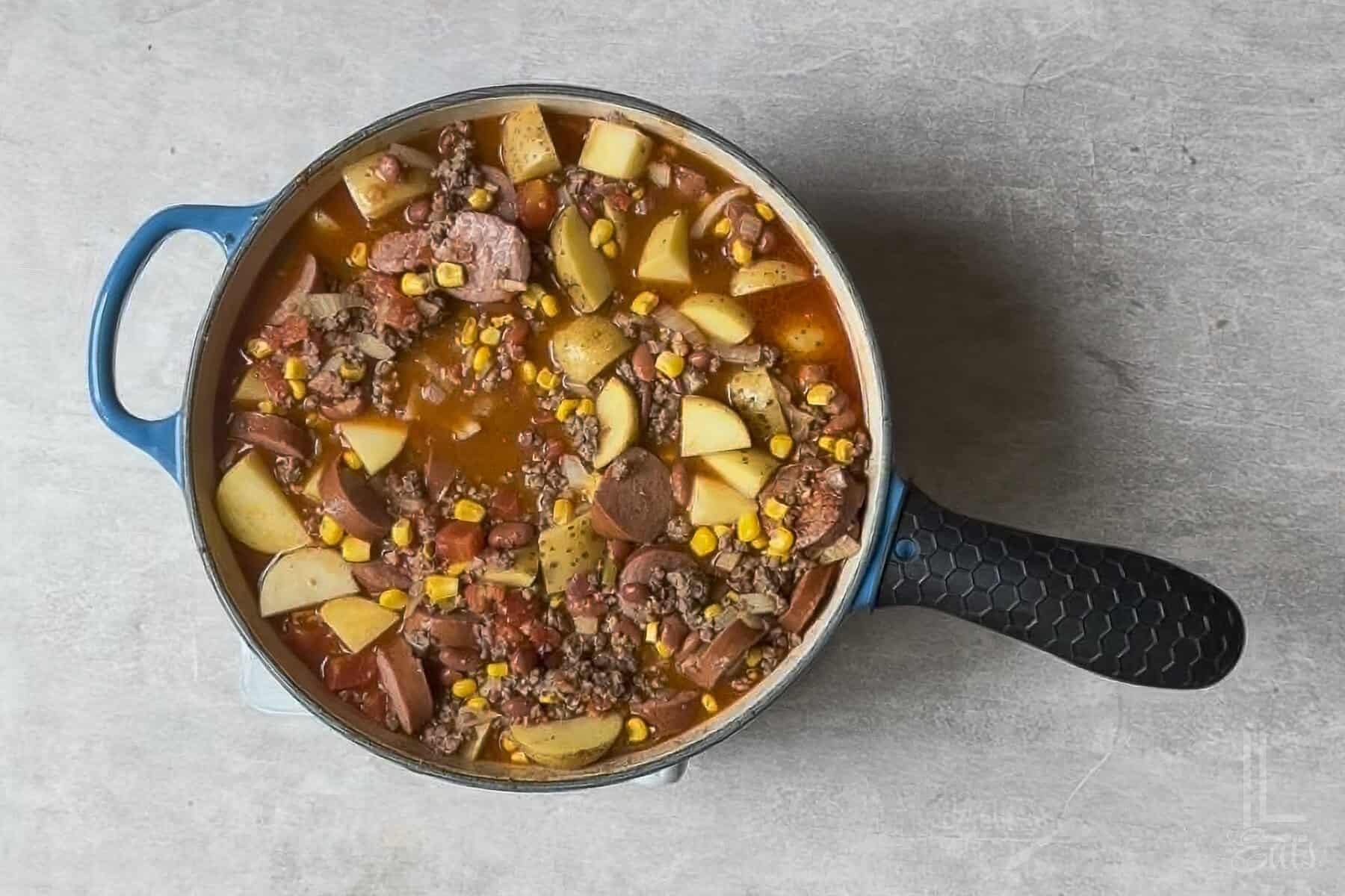 cowboy stew, with potatoes added, simmering in a large pot.