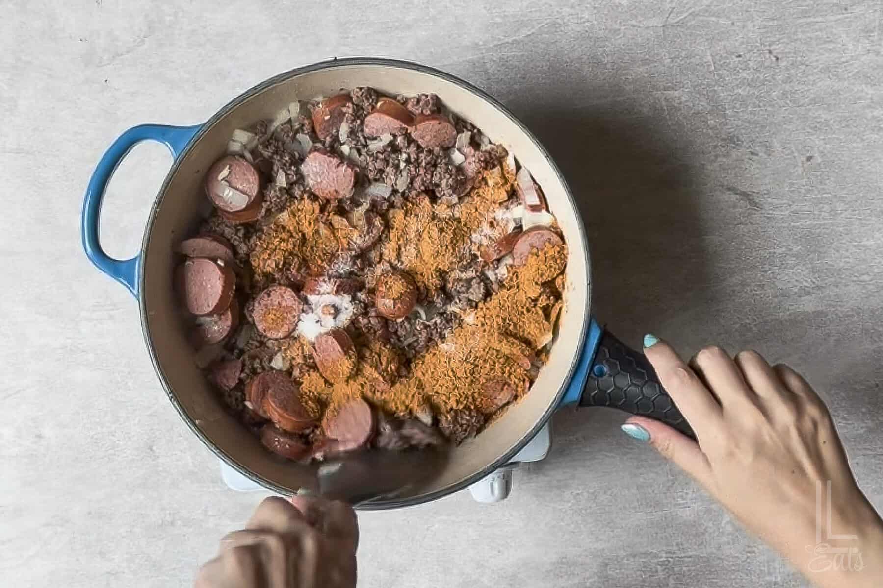 adding taco seasoning and salt to the meat mixture in the pot.