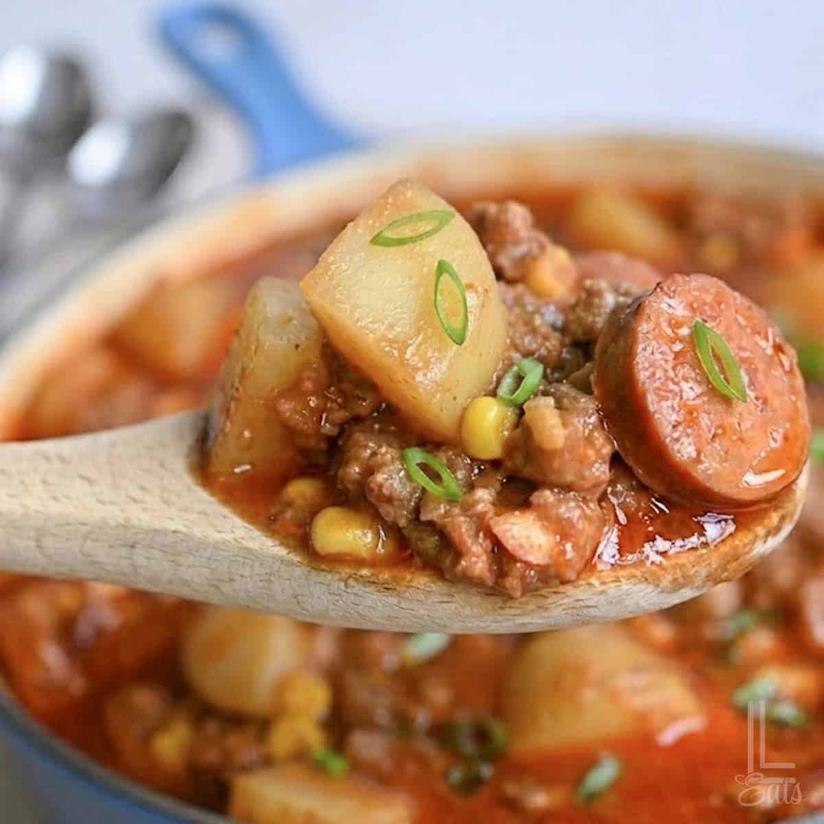 a spoonful of cowboy stew, including potatoes, corn, and kielbasa.