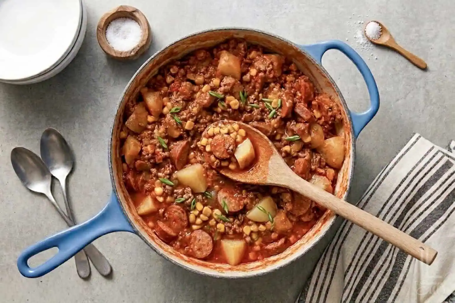 a large pot of cowboy stew, showing potatoes, kielbasa sausage, ground beef, and corn in a hearty soup.