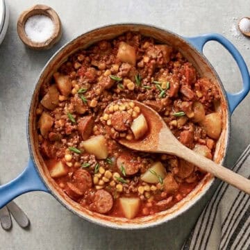 a large pot of cowboy stew, showing potatoes, kielbasa sausage, ground beef, and corn in a hearty soup.