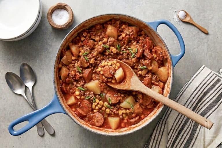 a large pot of cowboy stew, showing potatoes, kielbasa sausage, ground beef, and corn in a hearty soup.