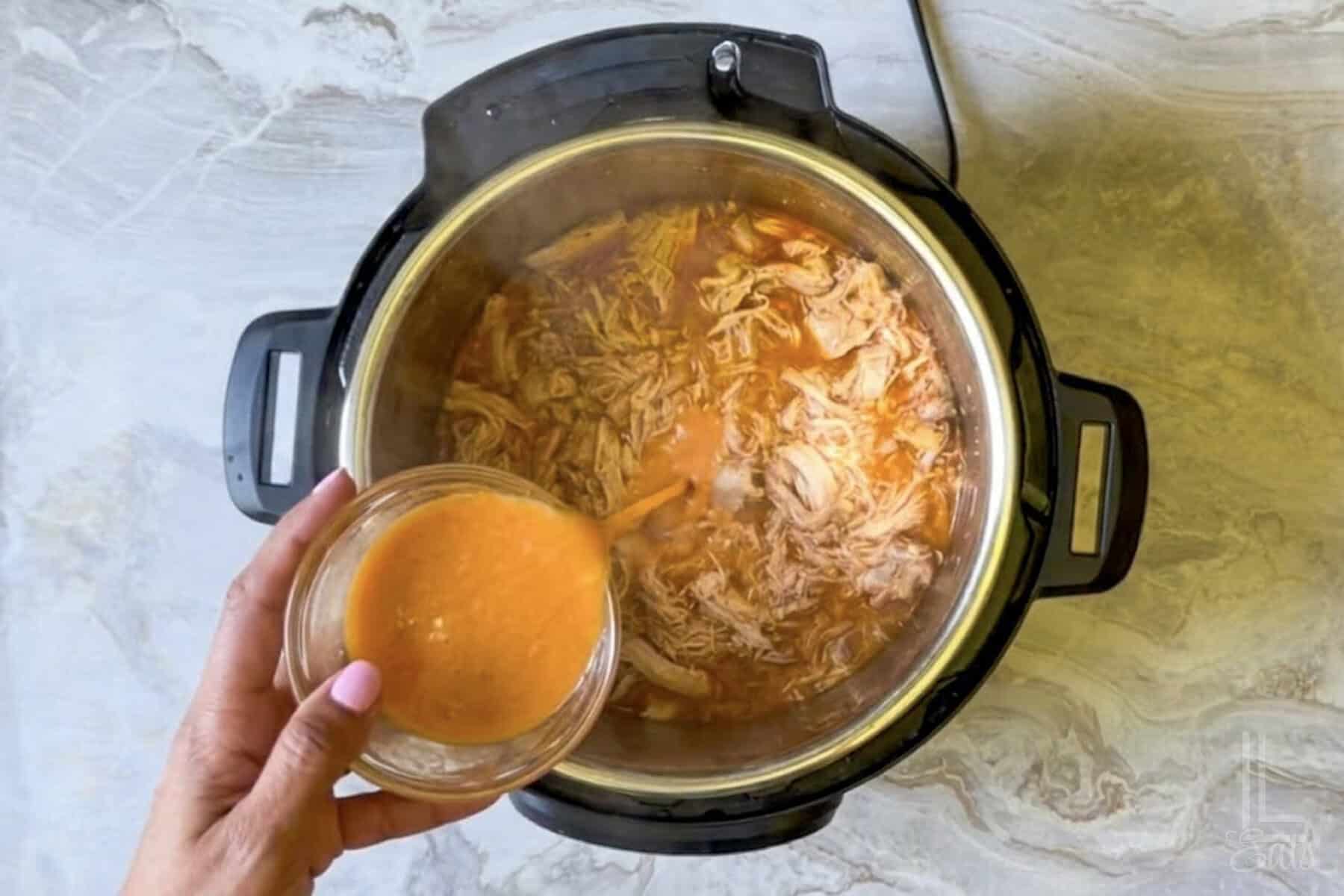 adding a cornstarch slurry to the shredded instant pot buffalo chicken.