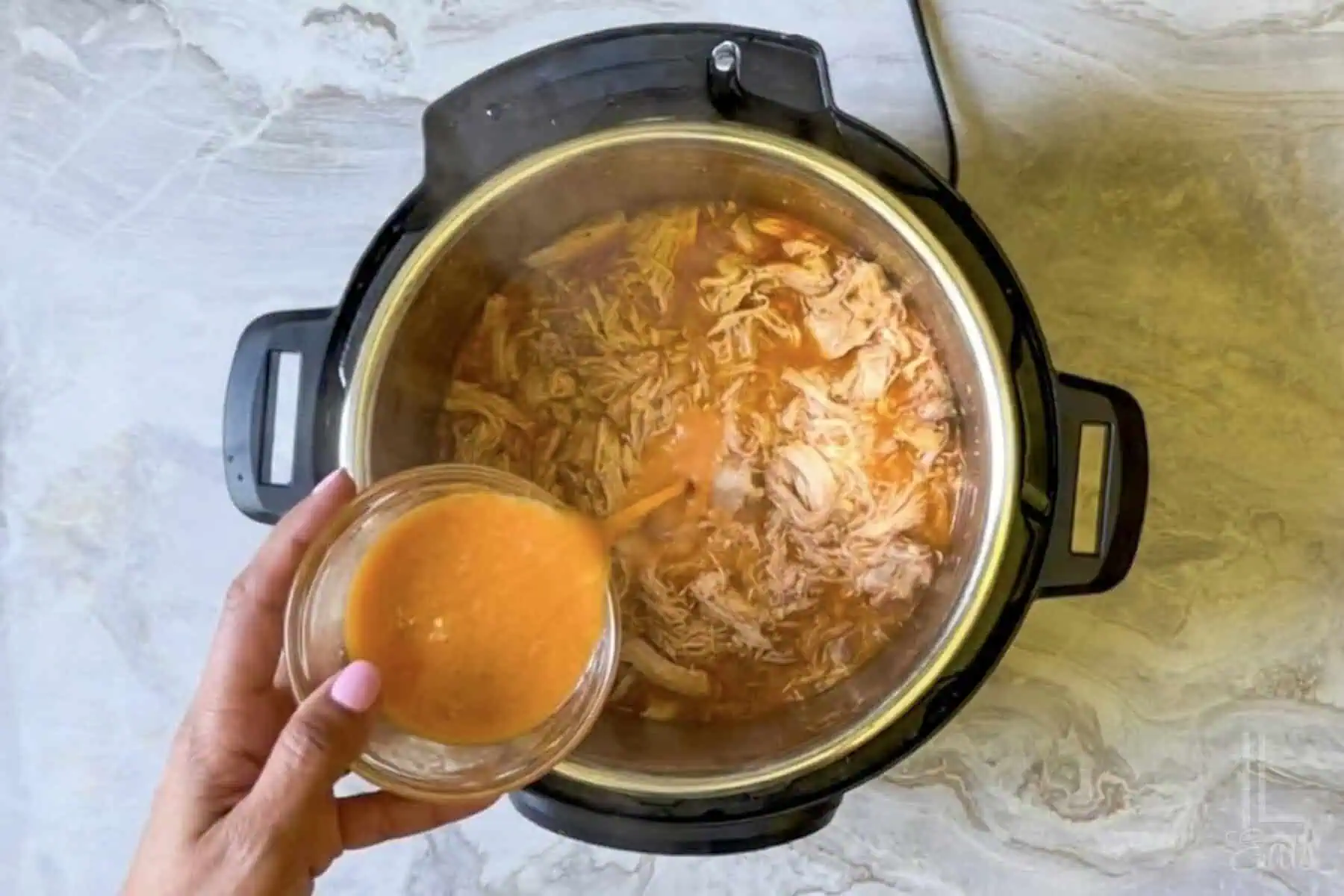 adding a cornstarch slurry to the shredded instant pot buffalo chicken.