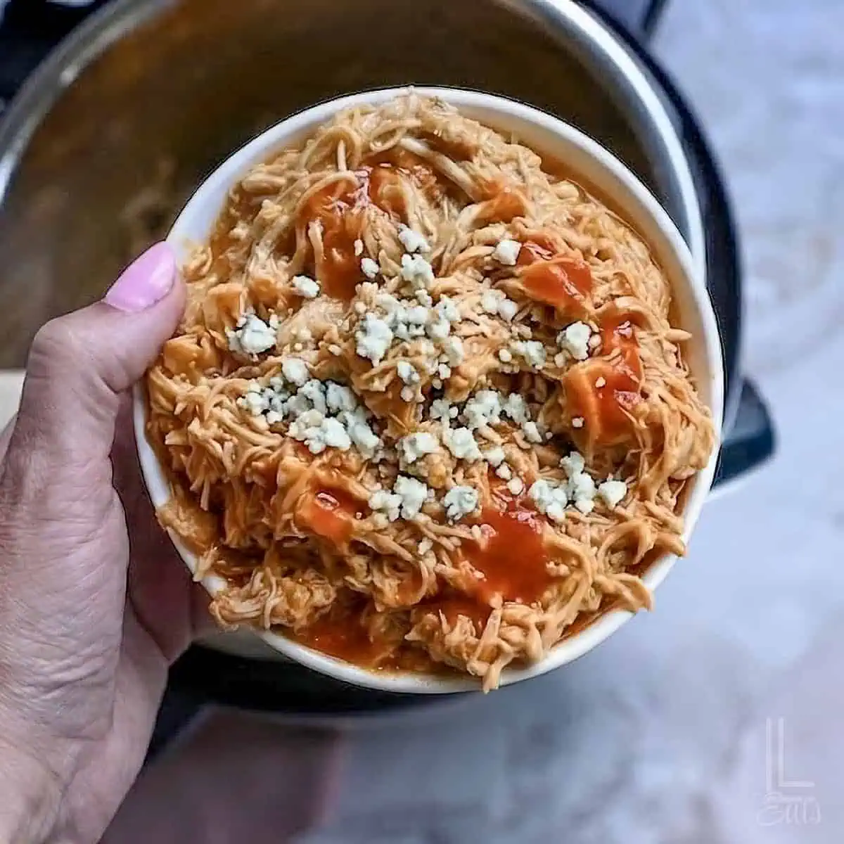 Creamy shredded chicken with buffalo sauce and blue cheese in a bowl.