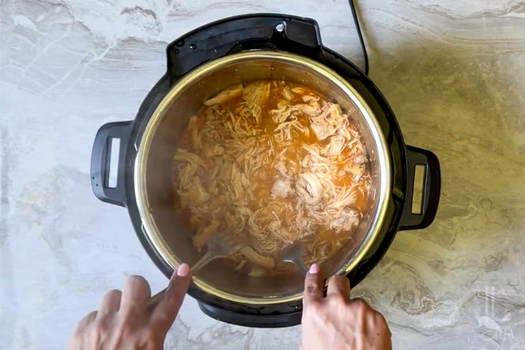 shredding the instant pot buffalo chicken with 2 forks.