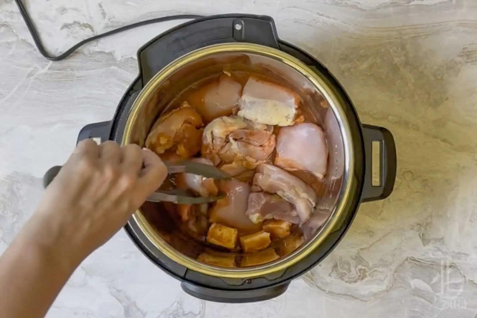 adding boneless, skinless chicken thighs to the hot sauce mixture in the instant pot.