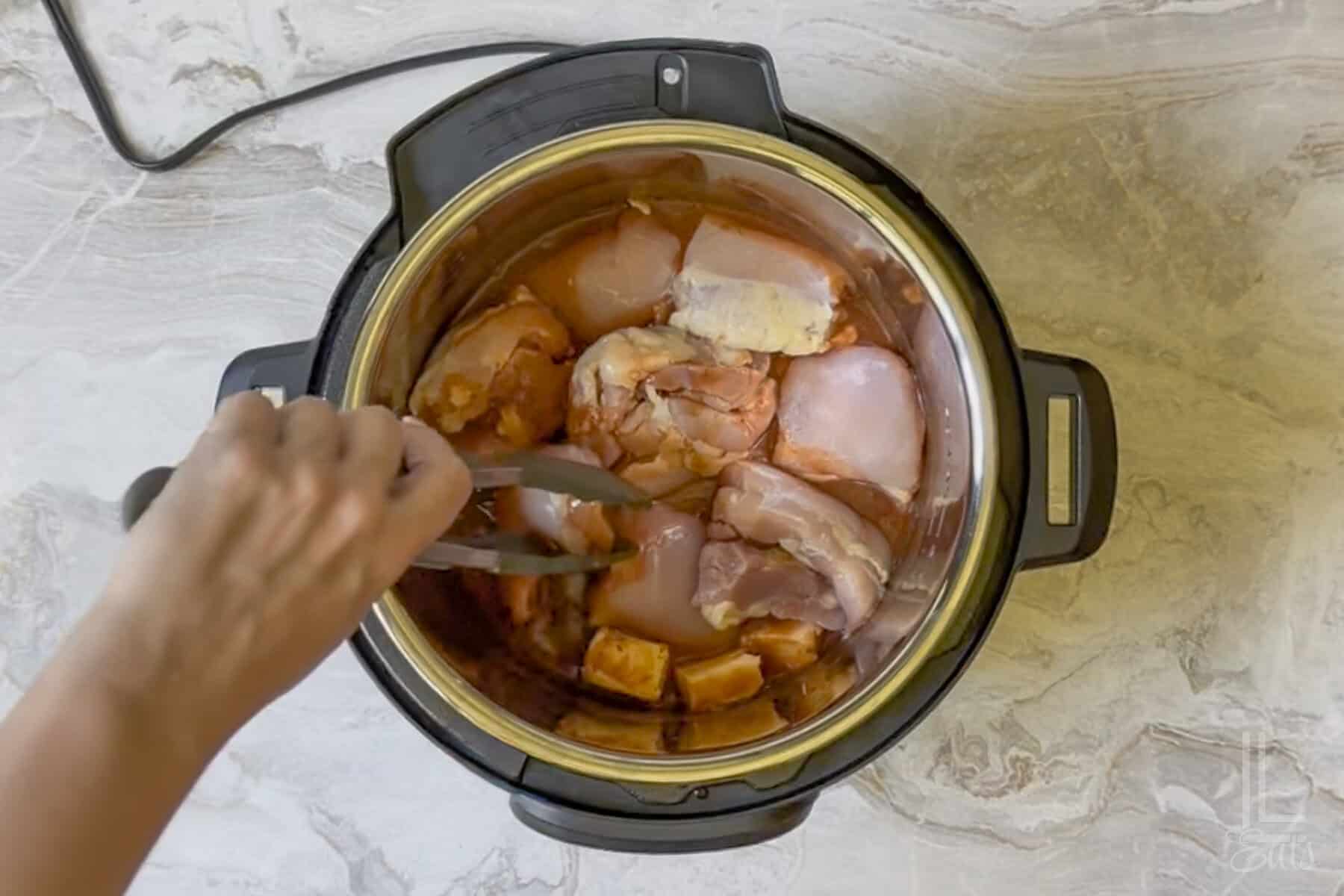 adding boneless, skinless chicken thighs to the hot sauce mixture in the instant pot.