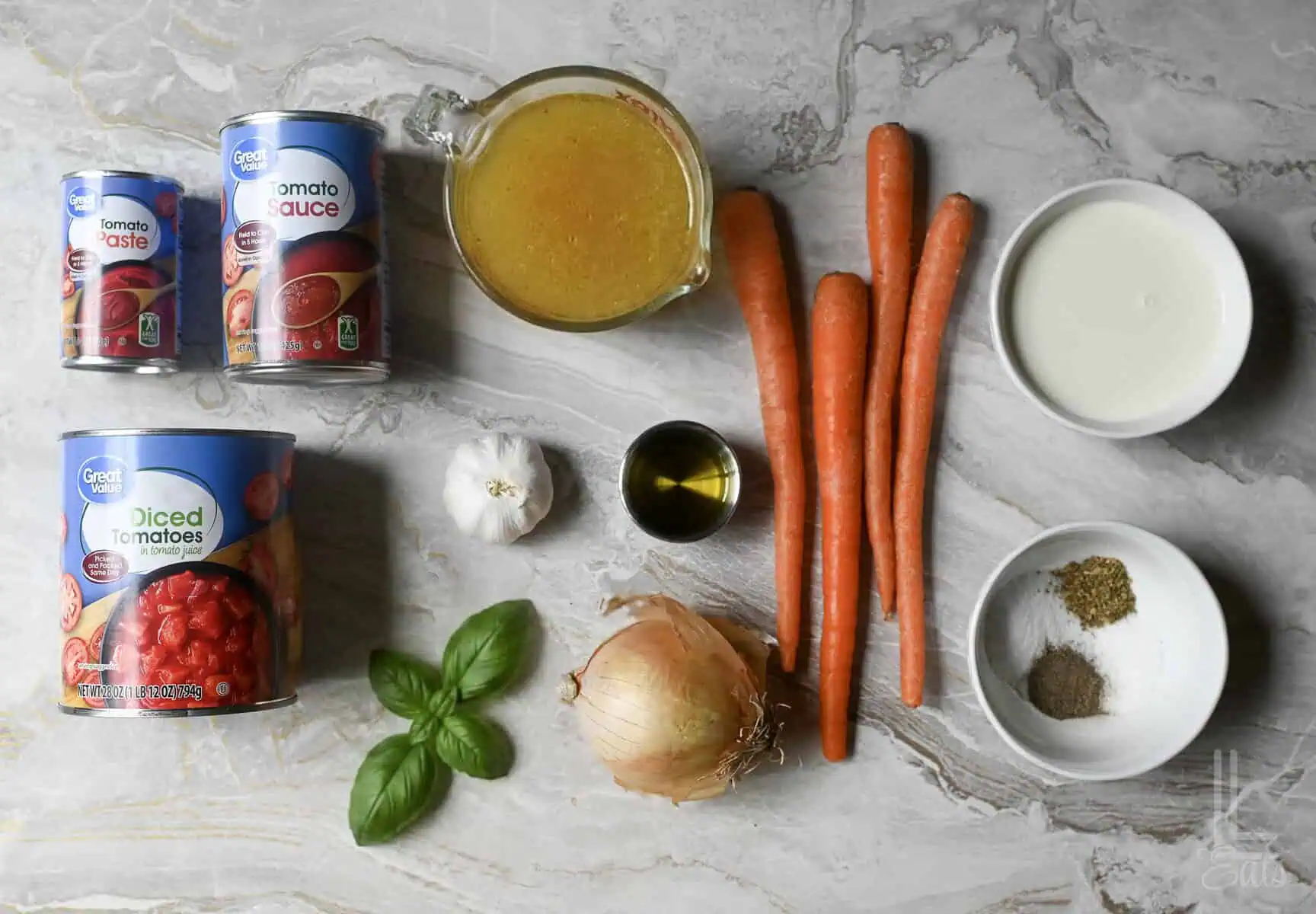 ingredients for instant pot tomato soup, including canned tomatoes, carrots, basil, and half and half.