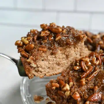 lifting a piece of pecan upside down cake off of a plate with a serving knife.
