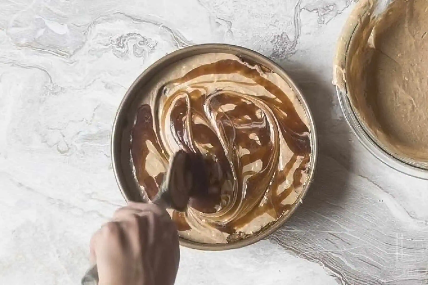 swirling the reserved caramel into the spice cake batter in the cake pan.