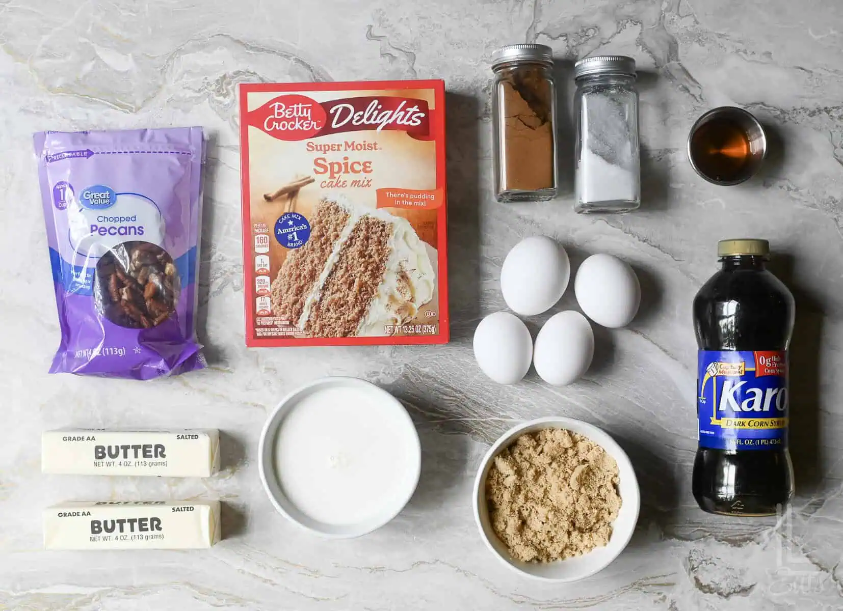 ingredients for pecan upside down cake, including spice cake mix, pecans, brown sugar, and corn syrup.