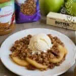 Apple crumble with pecans, oats, and vanilla ice cream on a white plate.