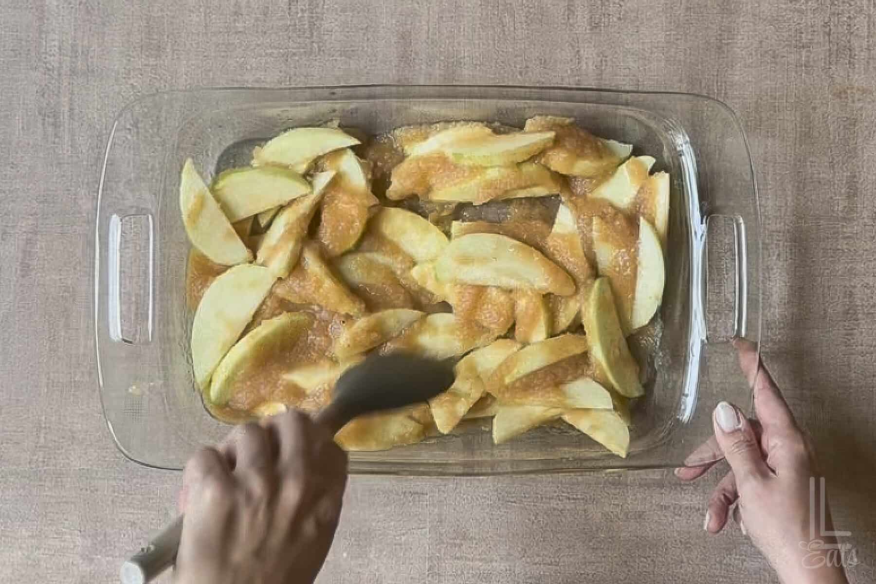 baking dish filled with sliced apples and applesauce stirred together.